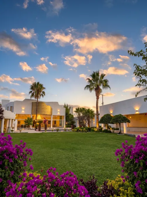 Jardines de Hacienda de Samotracia al atardecer con buganvilias y palmeras.